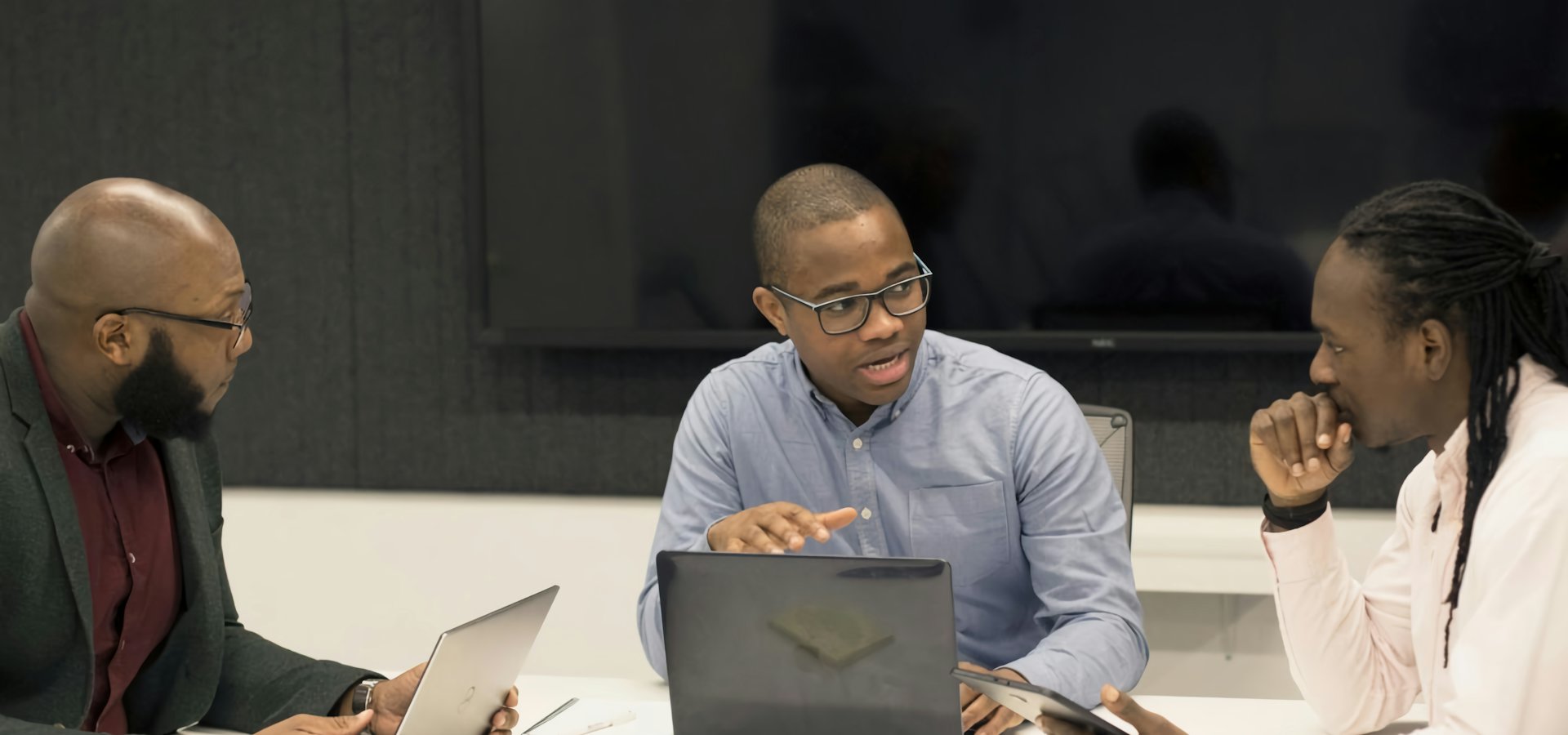Advisors in a strategy discussion around a laptop