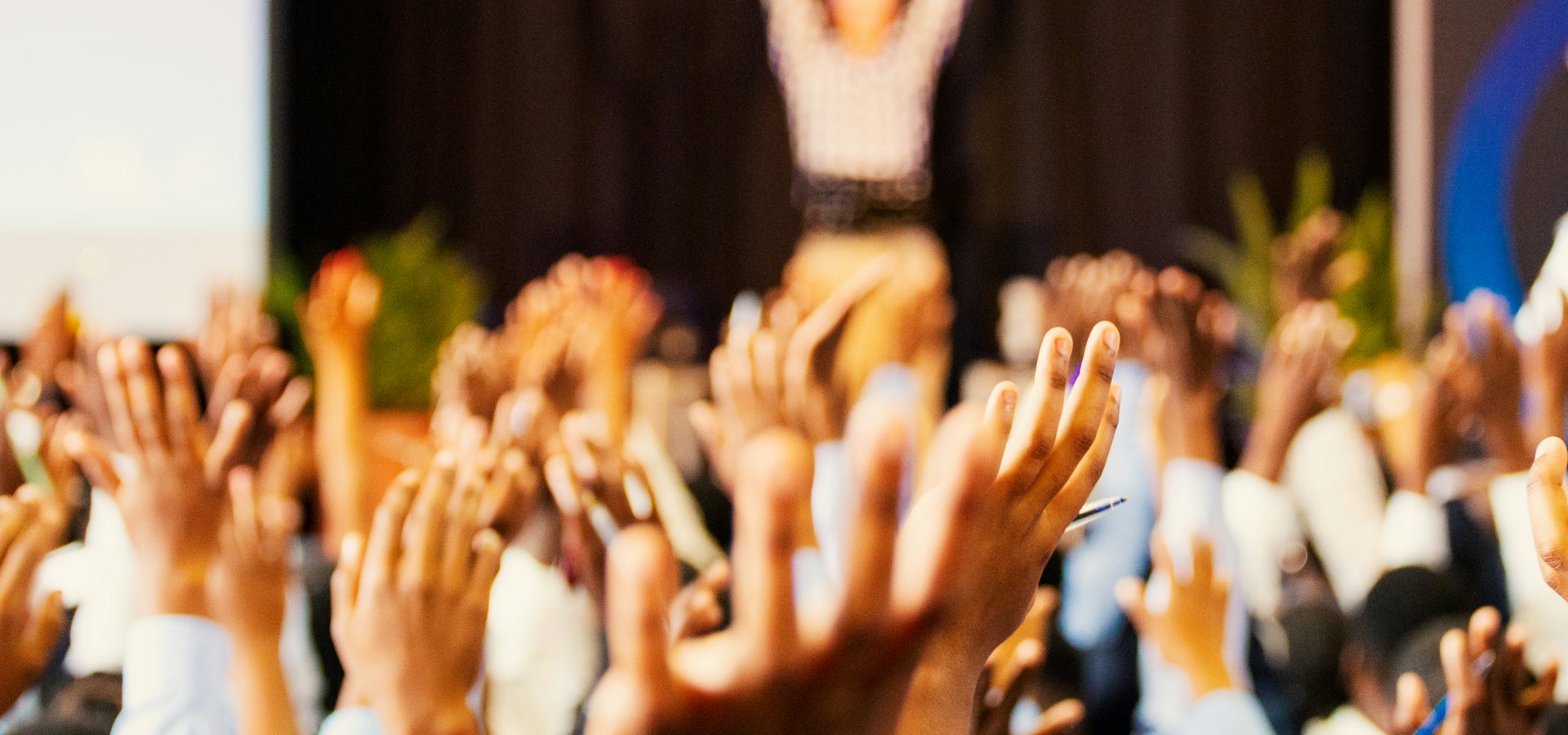 An energised audience raising their hands during an interactive group session